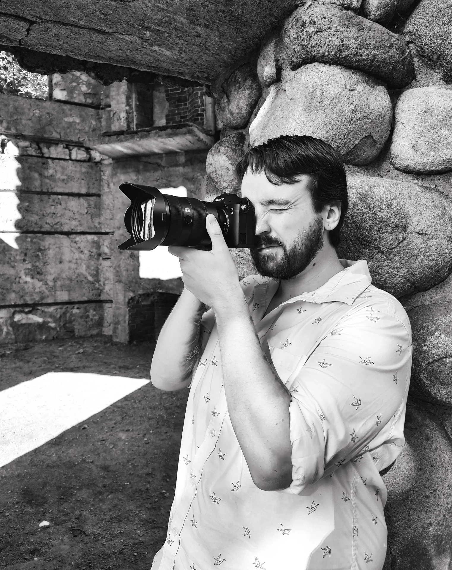 James Calnan III shooting with a camera beside a stone wall
